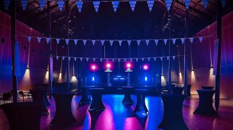 Installation DJ avec éclairages bleus et roses dans une salle événementielle, préparée pour une soirée dansante en région lyonnaise.