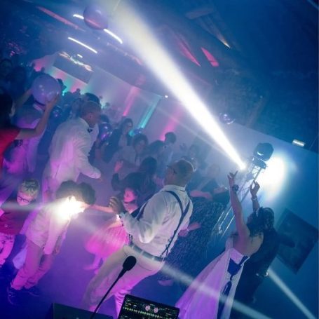 Invités en train de danser lors d’une soirée de mariage, avec éclairages blancs et violets et ambiance festive en région lyonnaise.